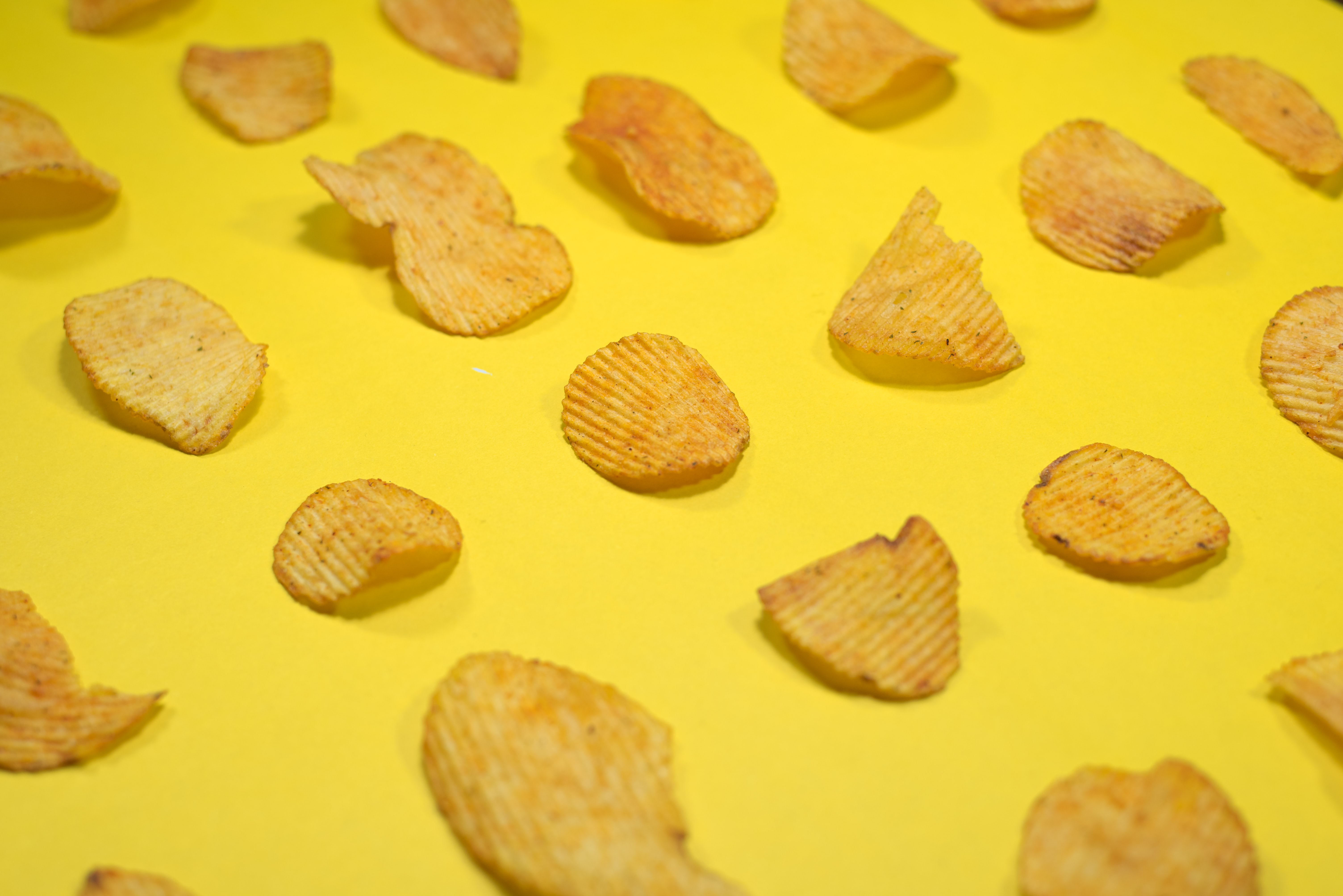 Yellow background with yellow potato chips laid in pleasing rows with spaces between each chip