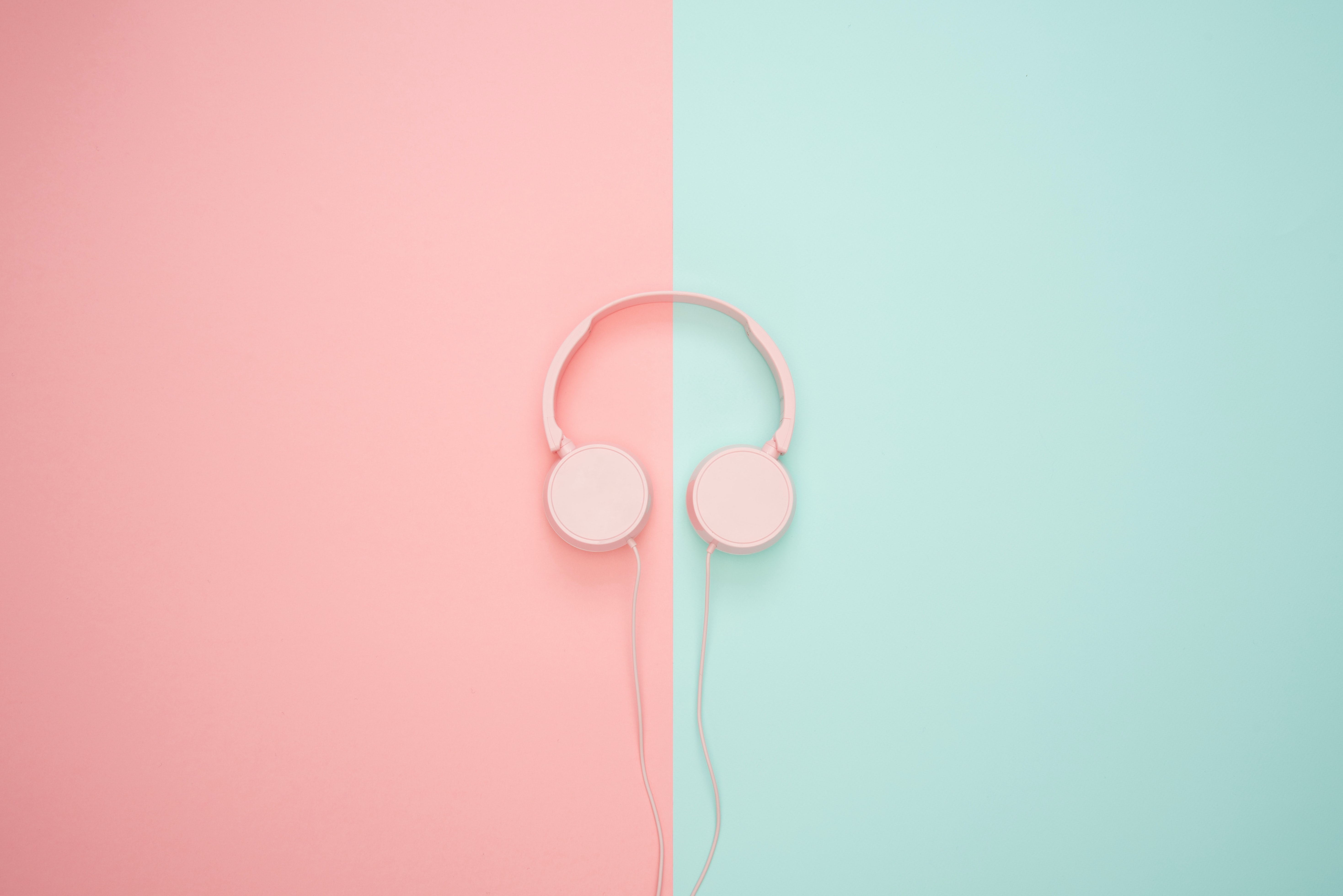 Pink and green background with pink headphones sitting in the center.
